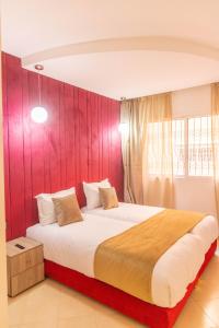 1 dormitorio con 1 cama grande y pared roja en Residence La Perle de l'Atlas Marrakech, en Marrakech
