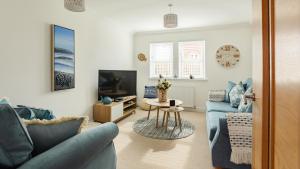 a living room with a blue couch and a tv at Wee Jules By The Sea in Anstruther