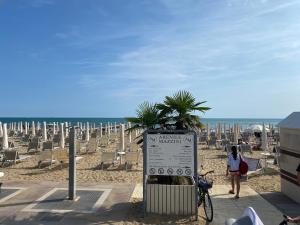 una spiaggia con sedie e un cartello sulla sabbia di Hotel Mazzini a Lido di Jesolo