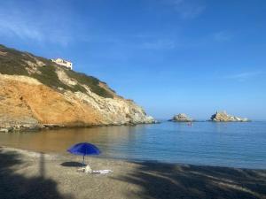 una sombrilla azul sentada en una playa junto al agua en Cosy Studio for couples 2 min from Mades Beach, en Ligaria
