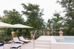 un patio con piscina, sillas y sombrilla en Cavalta Boutique Hotel GL, en Sevilla