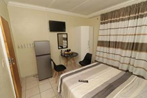 a bedroom with a bed and a refrigerator and a table at Quintax Guest House in Pretoria
