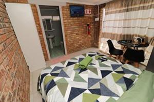 a room with a bed and a table and chairs at Quintax Guest House in Pretoria
