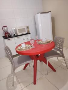 einen roten Tisch in einer Küche mit 2 Stühlen in der Unterkunft Casa mobiliada de 2 quartos na R Oliveira Alves Fontes, 609 - Jardim Gonzaga in Juazeiro do Norte