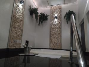 La salle de bains est pourvue d'une baignoire avec des plantes sur le mur. dans l'établissement MOTEL LA FOLIA, à Ribeirão Preto