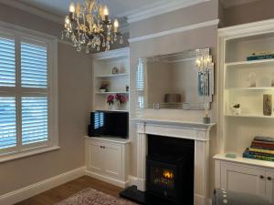 a living room with a fireplace and a chandelier at The Lily Pad - Cheltenham Townhouse, a short walk to Town Center and Racecourse in Cheltenham