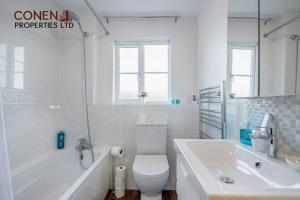 a white bathroom with a tub and a toilet and a sink at Captivating 2-Bed Apartment in Grays in West Thurrock