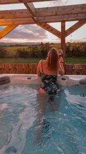 a woman taking a picture in a swimming pool at Timber Valley Pods in Galston
