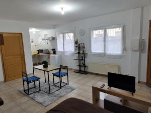 a living room with a table and chairs and a kitchen at Cosy Studio in Pont-de-lʼArche