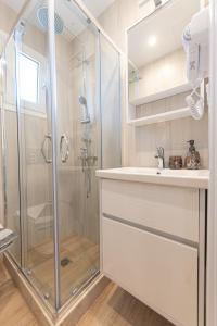 a white bathroom with a shower and a sink at Kanela Apartment - Hellenic Apartments Avlona in Oinófita