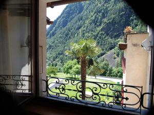 a window with a view of a palm tree and mountains at Al Piazzo 414 in Brusio