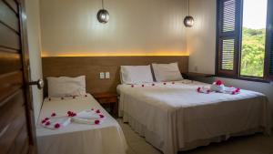 two beds in a hotel room with red and white decorations on them at Hotel Chale Nosso Sítio in Guaramiranga