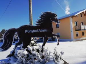 una estatua de un caballo corriendo en la nieve en Ponyhof Adam Urlaub auf dem Bauernhof, en Eschlkam