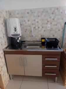 a kitchen counter with a sink and a microwave at Aconchego da Kika in Caruaru