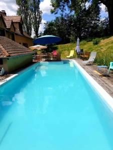 ein großer blauer Pool mit Stühlen und einem Sonnenschirm in der Unterkunft Cottage Saint Martin in Ozolles