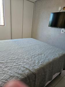 a bed in a room with a white bedsheet at Iloa Residence Apt Premium -Quarto e sala climatizado in Barra de São Miguel