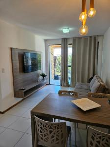 a living room with a table and a television at Iloa Residence Apt Premium -Quarto e sala climatizado in Barra de São Miguel