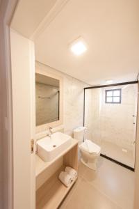 a white bathroom with a sink and a toilet at Loft completo e aconchegante in Canela