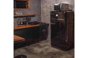 a kitchen with a refrigerator with a microwave on top of it at Cabana Carcará in São Bento do Sapucaí