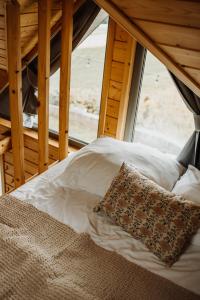 a bed with a pillow in front of a window at Loft&Hill in Grywałd