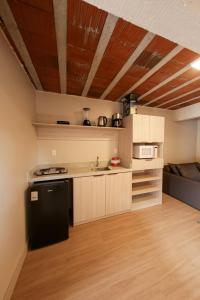 uma pequena cozinha com um frigorífico preto num quarto em Loft completo e aconchegante em Canela