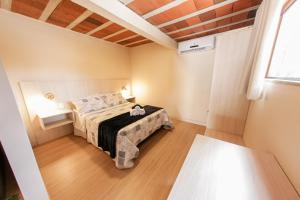 um pequeno quarto com uma cama e uma janela em Loft completo e aconchegante em Canela