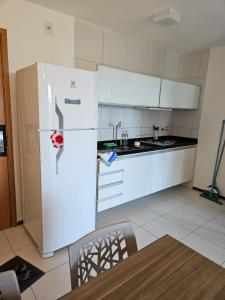 a kitchen with a white refrigerator and a sink at Iloa Residence Apt Premium -Quarto e sala climatizado in Barra de São Miguel