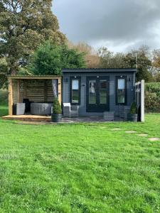 una casita azul en un campo de hierba en Dolafon farm luxury glamping cabin with hot tub, en St Asaph