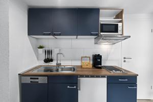 a kitchen with blue cabinets and a sink at ADN Suites - NETFLIX - modern and smart in Günzburg