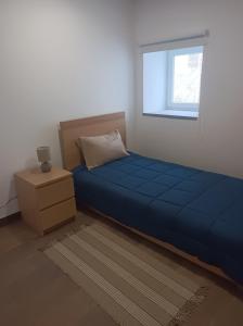 a bedroom with a blue bed and a window at Casa Amado Fundão in Fundão