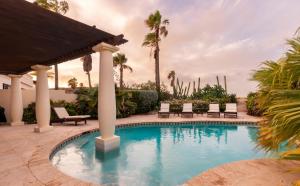 a swimming pool with chairs and palm trees at Luxurious Ocean View Tierra del Sol Villa in Palm-Eagle Beach
