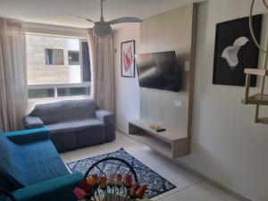 a living room with a blue couch and a tv at ISRAEL FLAT DUPLEX C/ PISCINA in João Pessoa