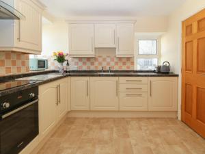 a kitchen with white cabinets and black appliances at Tonnau Waves in Pwllheli