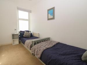 a bedroom with two beds and a window at Tonnau Waves in Pwllheli