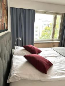 two red pillows sitting on a bed with a window at Spacious 2 rooms apartment in Helsinki Design District, own balcony in Helsinki +12 photos