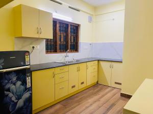 a kitchen with yellow cabinets and a sink at AL-Kabeer Lavender budget rooms in Trivandrum