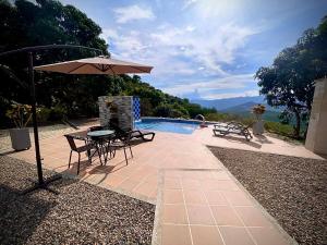 Casa Campestre Villa de los Angeles في لا ميسا: فناء مع طاولة ومظلة بجوار حمام سباحة