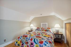 1 dormitorio con 1 cama con edredón colorido y 2 lámparas en Stowe Farmhouse Apartment, en Stowe