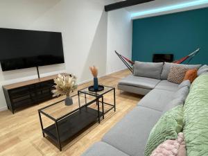 ein Wohnzimmer mit einem Sofa und einem Flachbild-TV in der Unterkunft Le Magnifique Spacieux - 6 personnes - 3 chambres avec SDB privatives - idéal entreprise in Lens