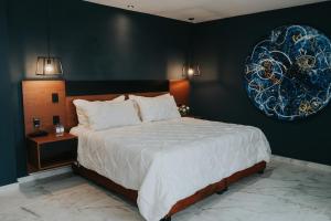 een slaapkamer met een groot bed en een schilderij aan de muur bij Hotel Casa Puga in Oaxaca City