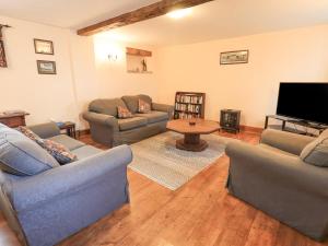 a living room with couches and a flat screen tv at The Byre in Cockermouth