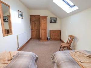 a bedroom with two beds and a mirror and a chair at The Byre in Cockermouth +18 photos