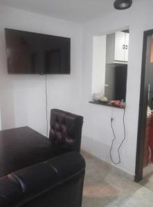 ein Wohnzimmer mit einem schwarzen Sofa und einem Flachbild-TV in der Unterkunft Casa prado alto in Barranquilla