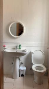 uma casa de banho com um WC, um lavatório e um espelho. em Double bedroom with ensuite in spacious corner apartment em Birkirkara