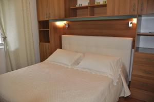 a bedroom with a white bed and wooden cabinets at Casa Vacanze Bouganvillea in Cetara