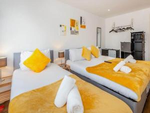 Cette chambre comprend 2 lits avec des oreillers jaunes et blancs. dans l'établissement Ws Apartments - Luxury 1 bed in Watford Central, à Watford