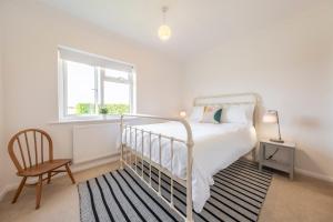 1 dormitorio con 1 cama, 1 silla y 1 ventana en Family water sports and cycling getaway - The Lake House en Ipswich