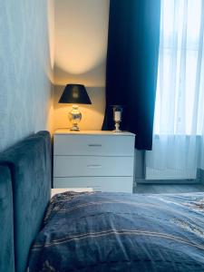 a bedroom with a bed and a dresser with a lamp at Apartament Oliwia in Szczecin