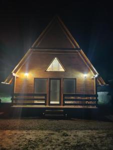 een houten huis 's nachts met de lichten aan bij ALI HOUSE in Poiana Fagului