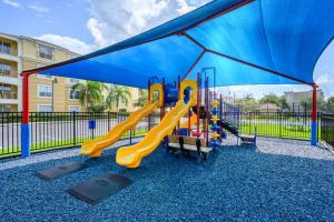 een speeltuin met een glijbaan en een blauwe baldakijn bij Apartment at Vista Cay Resort in Orlando